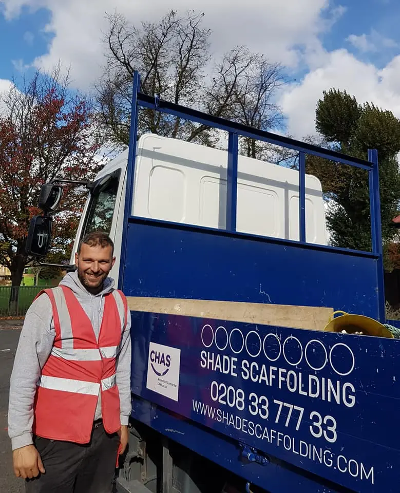 A man in a hi-vis vest beside the blue Shade Scaffolding lorry